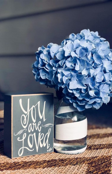 Glasvase mit blauen Blumen und einem Aussteller mit der Notiz you are loved